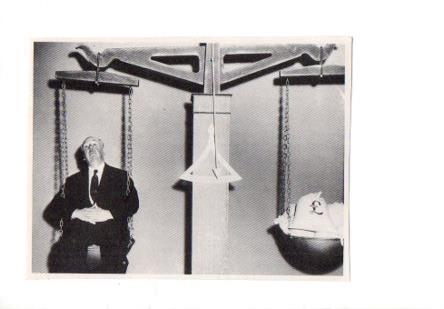 V48702: Alfred Hitchcock sentado en una balanza