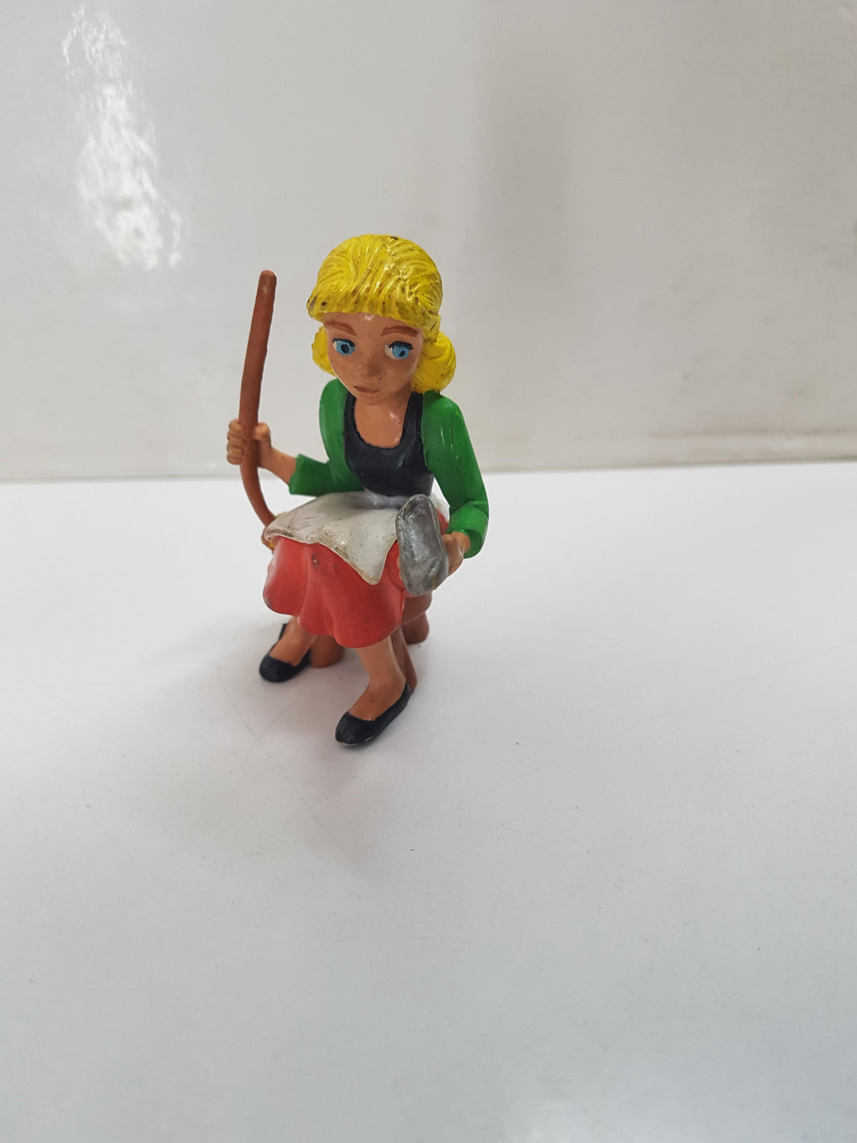 Figura de Cenicienta sentada en taburete, sujetando zapato y escoba 