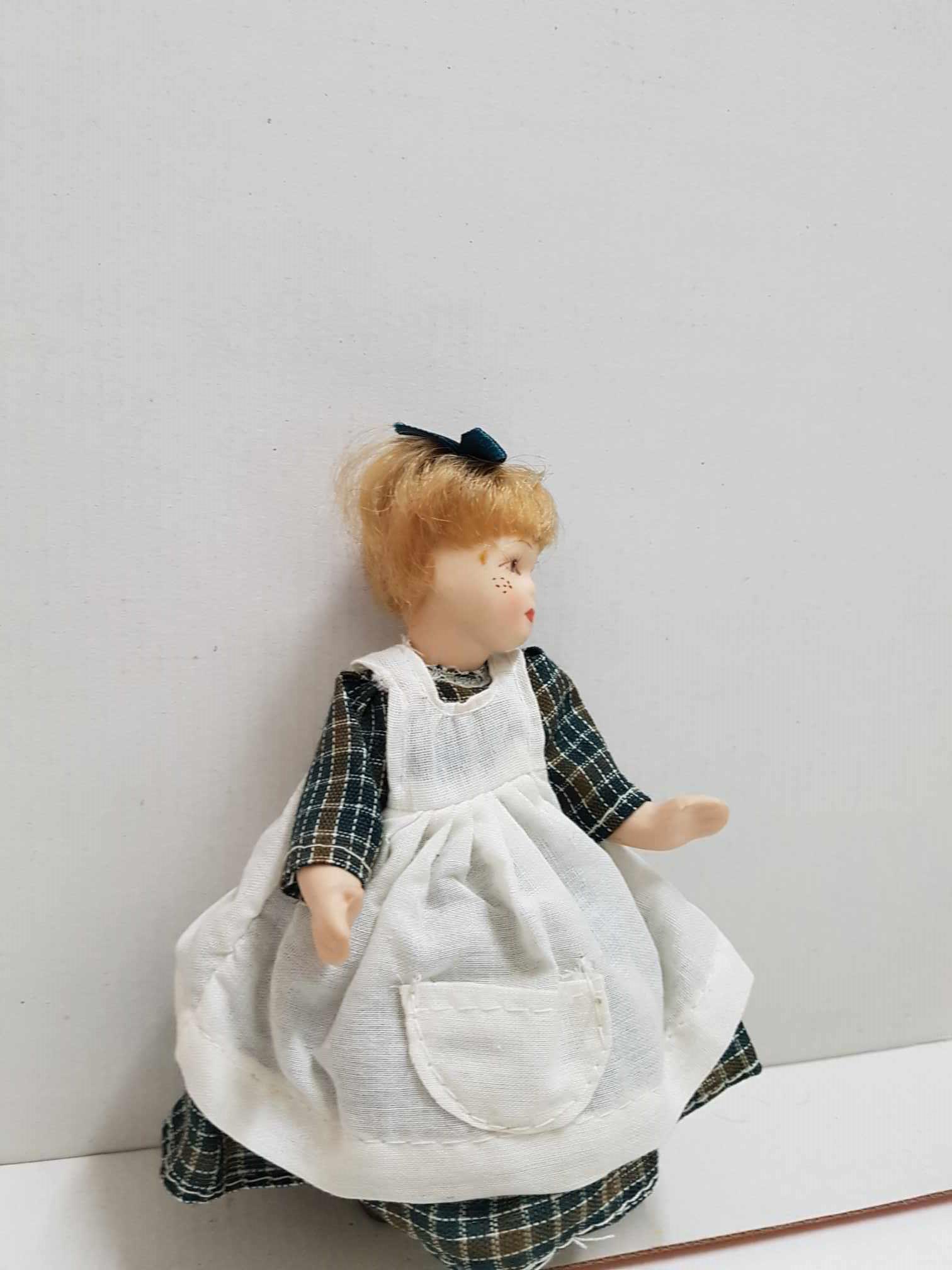 Figura de muñeca de porcelana años 80: niña con lazo en la cabeza, delantal y vestido a cuadros