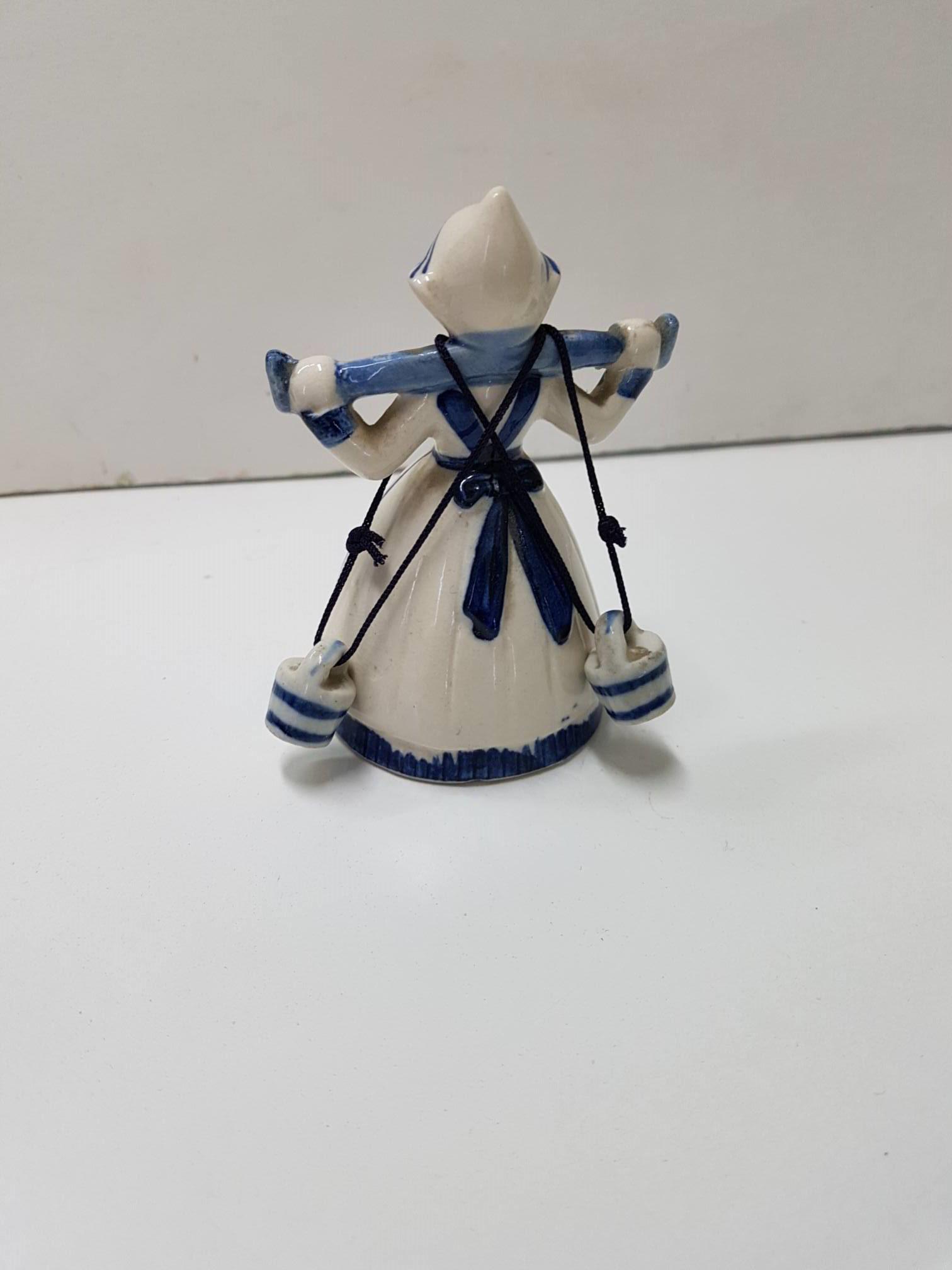 Figura de holandesa llevando dos cubos de leche, con molino de viento dibujado en el delantal.