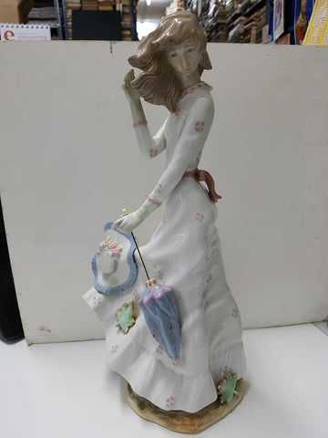 Figura de mujer vestido claro con paraguas y sombrero quitado. De ceramica