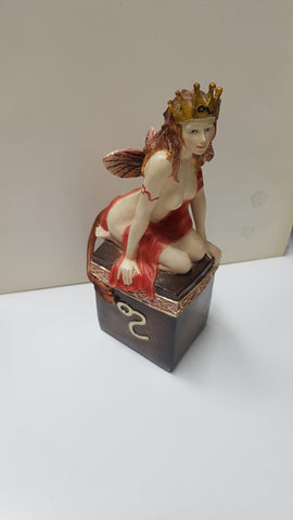 Figura de fantasia: Hada con diadema con forma de corona, de rodillas sobre un pedestal.