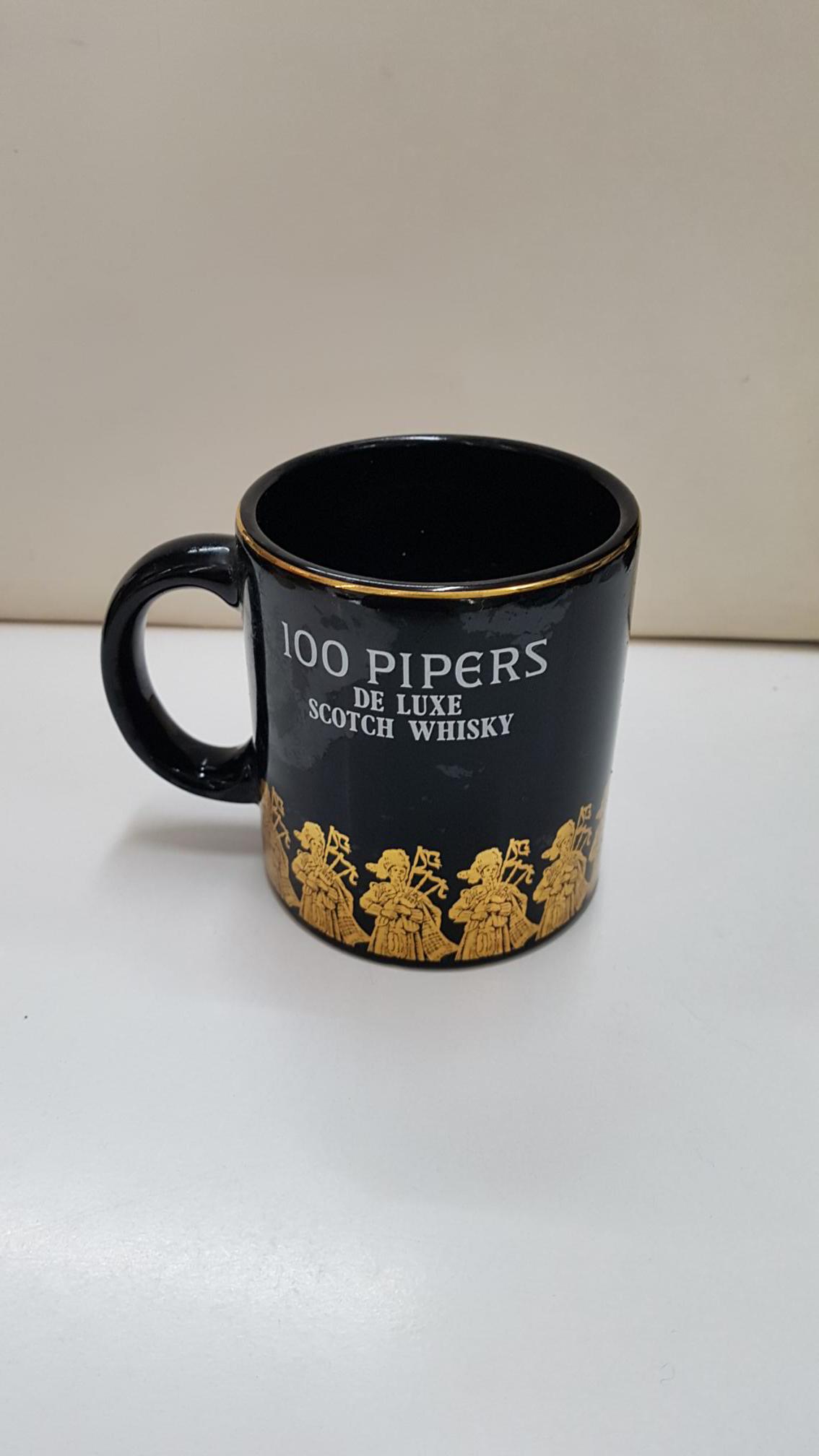 Taza negra de ceramica: 100 Pipers de Luxe Scoth Whisky.