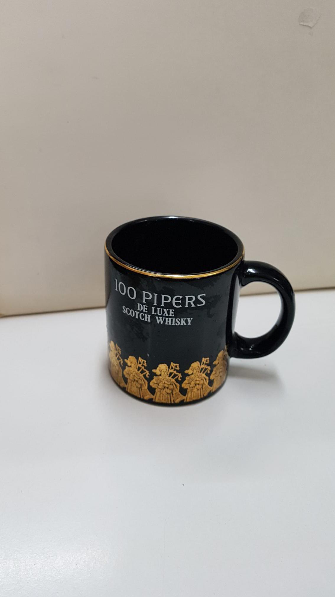 Taza negra de ceramica: 100 Pipers de Luxe Scoth Whisky.