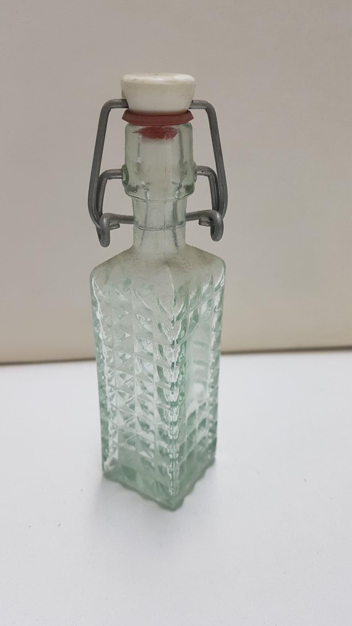 Botella  de cristal de tamaño mini con forma cuadrada y tapon mecanico. 13 cm de alto