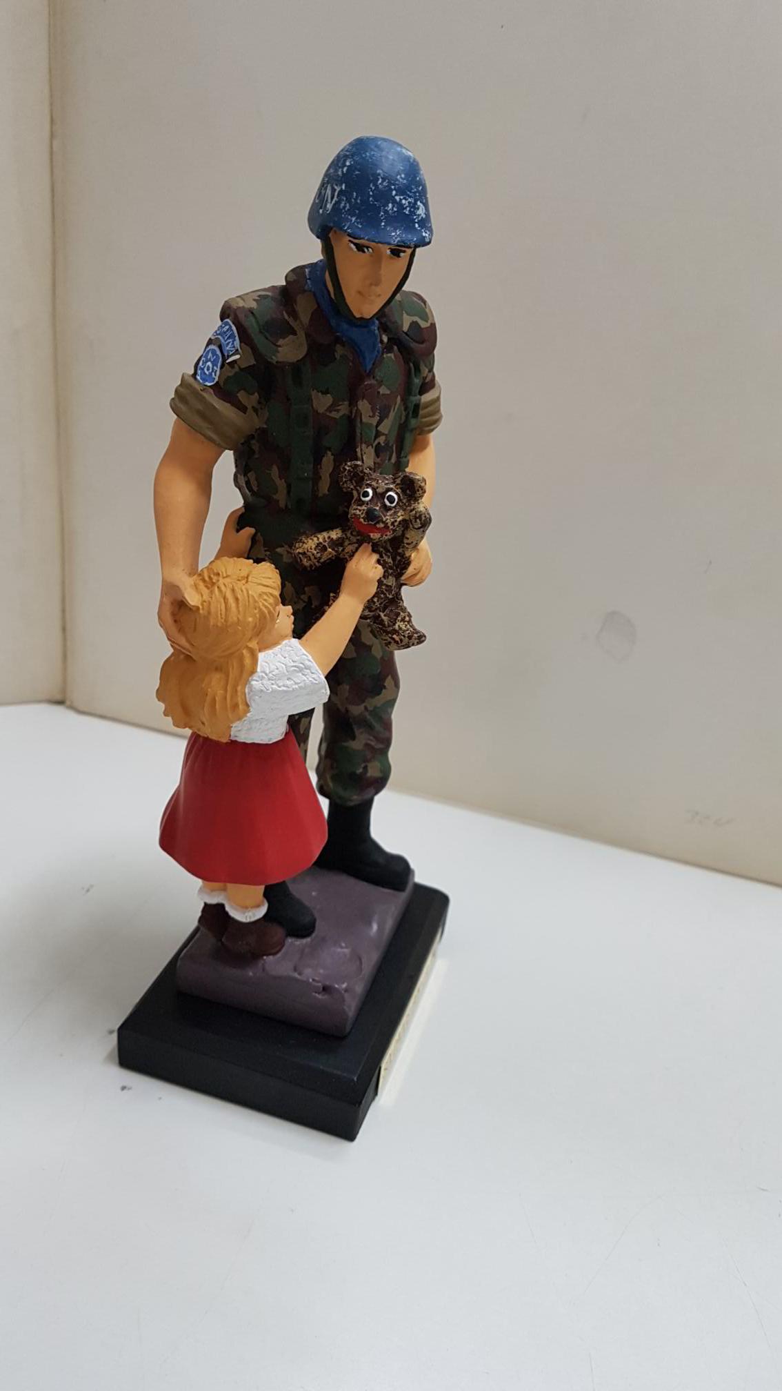Figura de resina artesanal: Soldado español perteneciente a Soldados por la Paz de N.U. dandole un oso a una niña