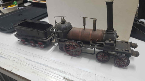 Replica de antigua locomotora de metal con un vagón de carga